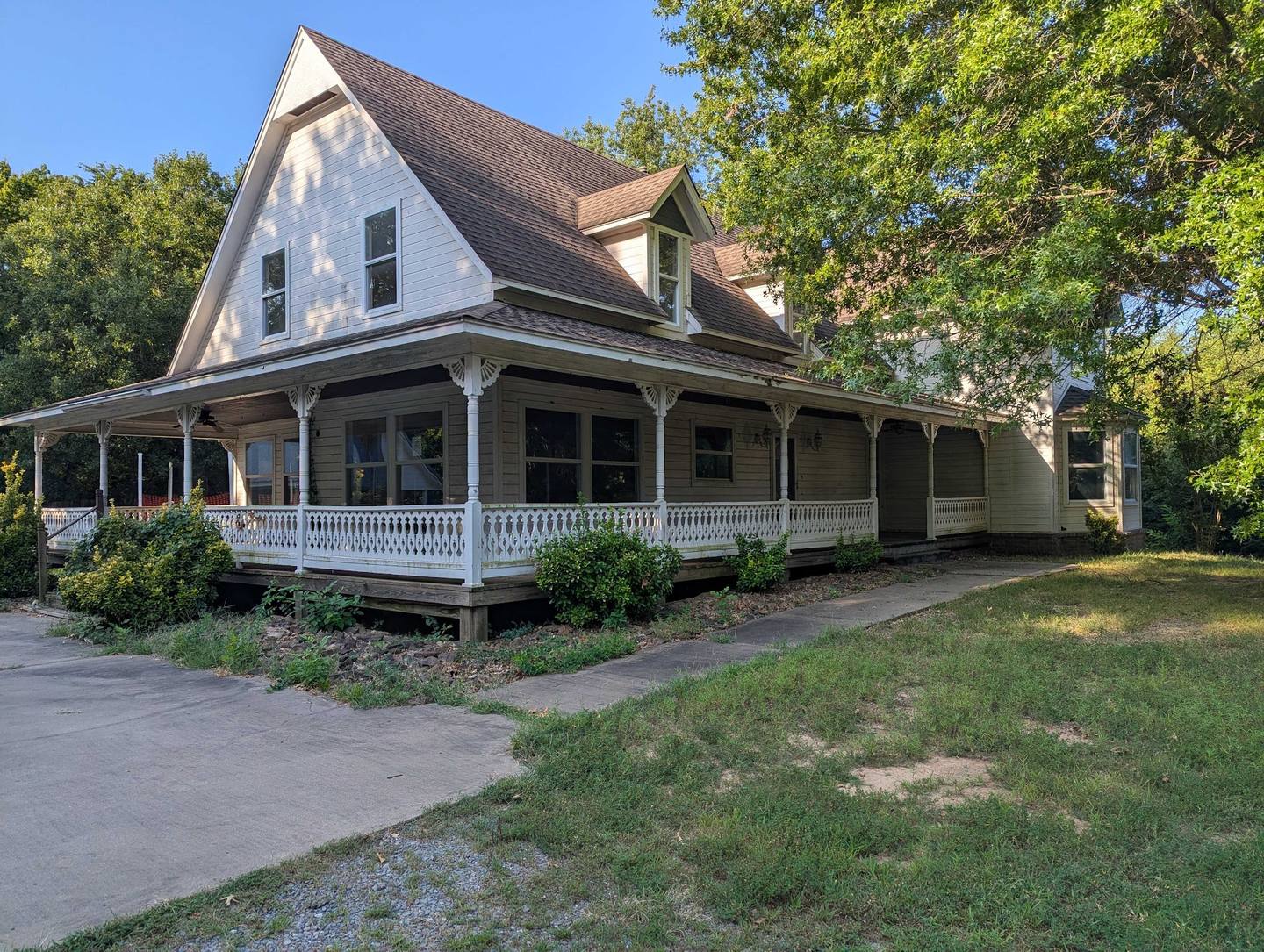 Older two-story home with a wraparound porch raised off the ground