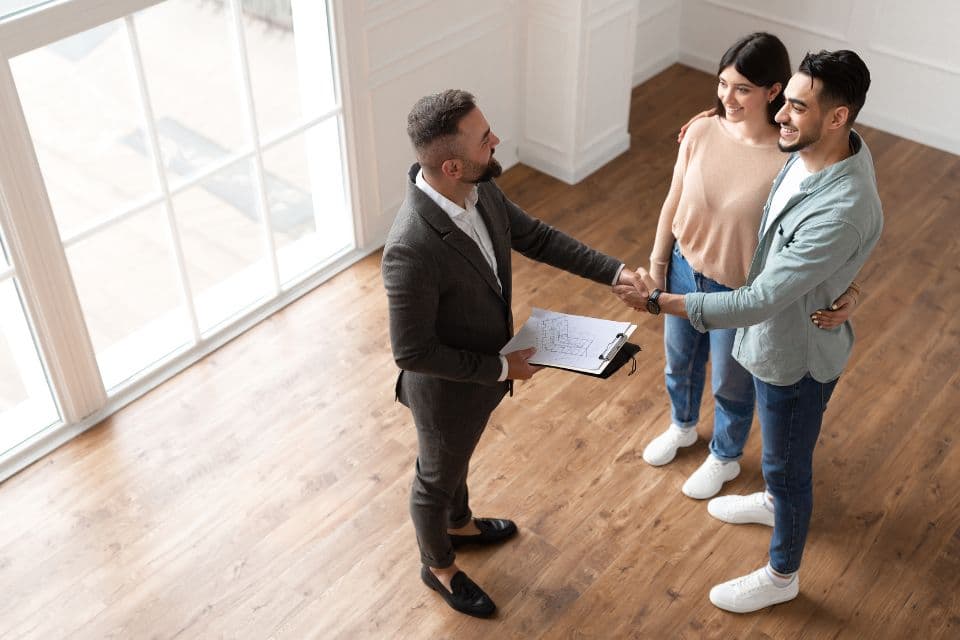 Real estate agent shaking hands with home buyers after a successful closing